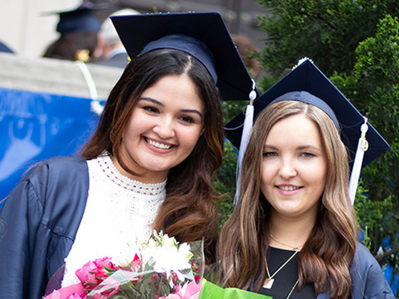 two smiling girls in graduation cap and gowns
